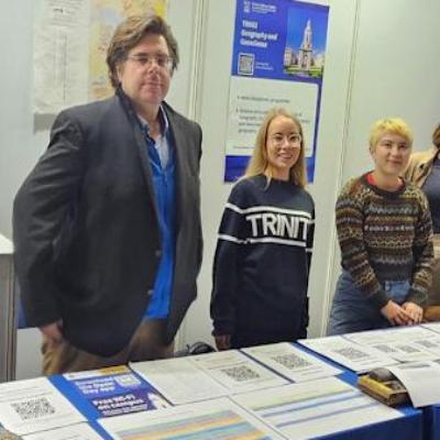 Staff member and students standing at Open day Table for Geosciences ready to talk to visitors